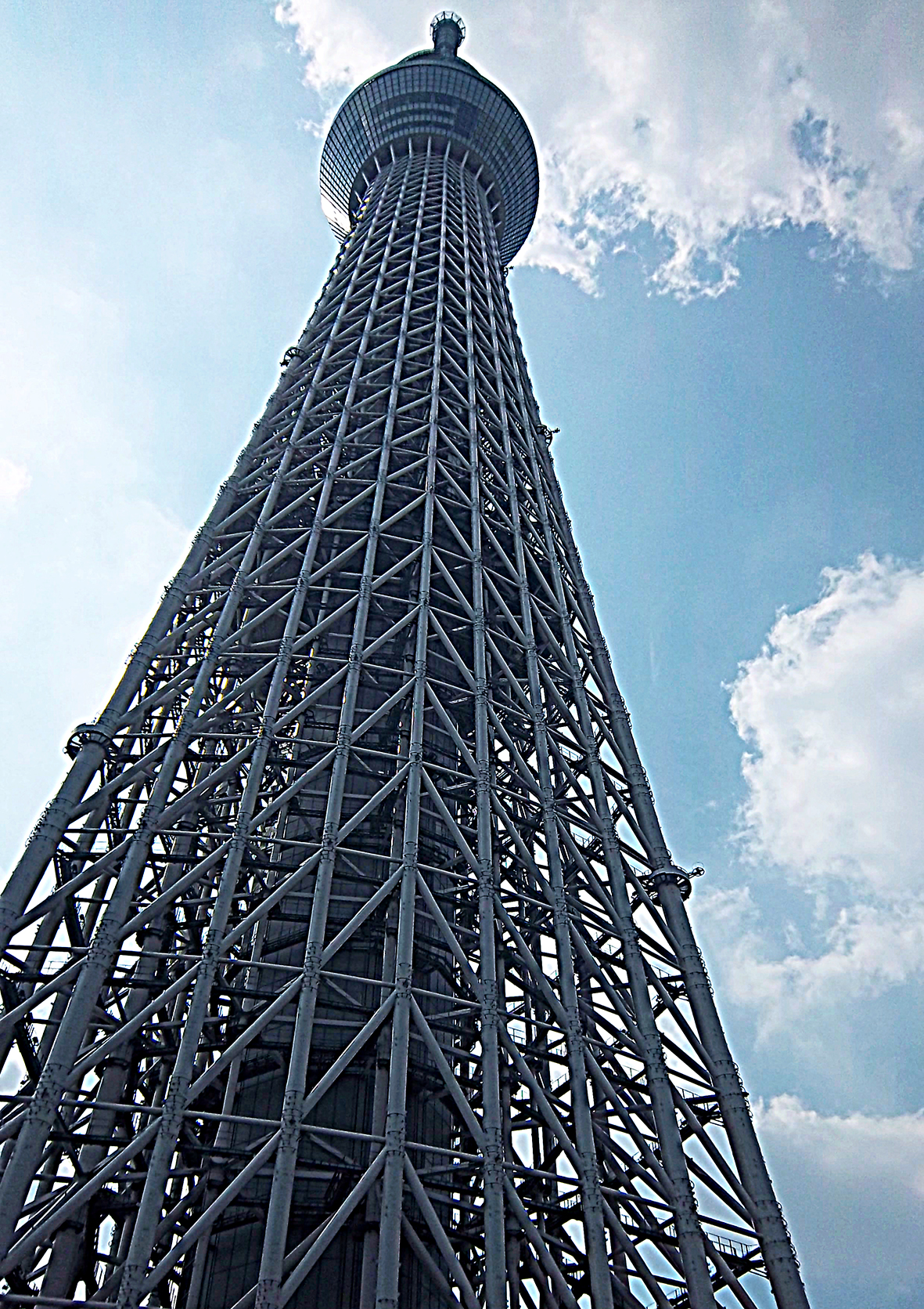 looking up through the scaffold-type construction of Skytree to the first disc-like viewing platform, and beyond into the blue sky.