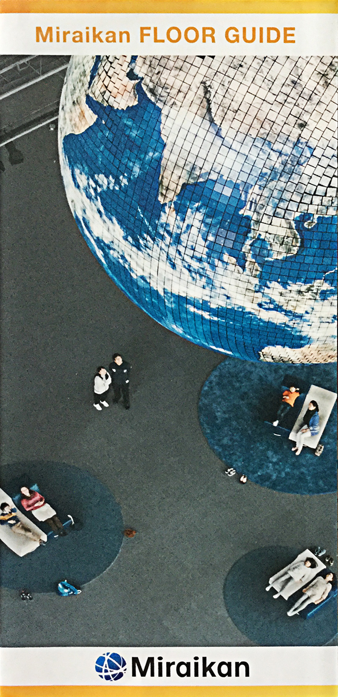 looking down on a predominantly ble and white model of the the earth hanging from the ceiling of the Maraikan, we catch a quarter of the globe, and the grey floor of the building with people, laying on blue circles, looking up.